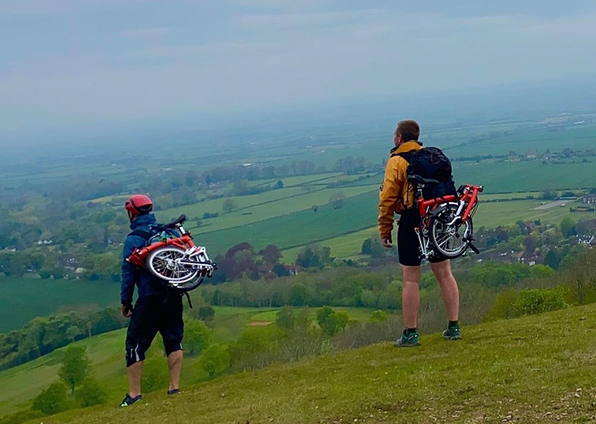Team standing on hill looking out to view with bikes on back
