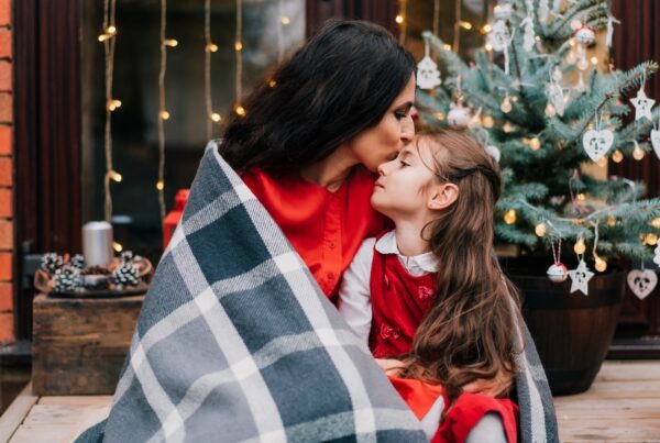 Mother hugging and wrapping her daughter in a blanket during the Festive Season.
