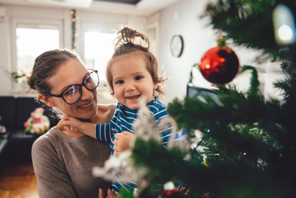 Mother holding daughter and decorating Christmas tree during the Festive Season.